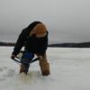 WJ14 7537 Man drilling hole in the ice wearing Tough Duck 3 in 1 parka and insulated bib overall